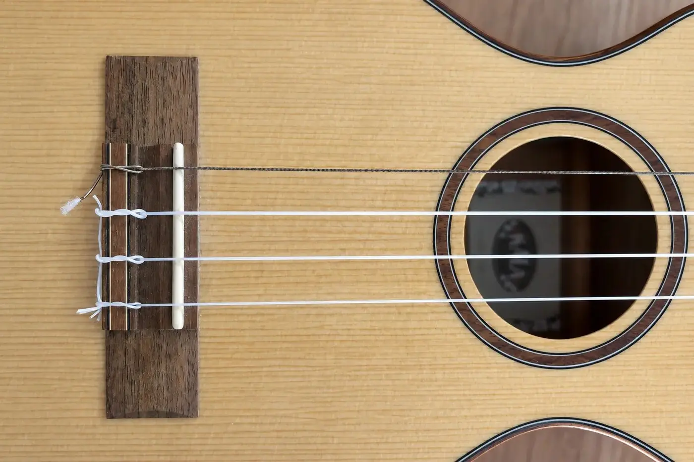 Tenor-Ukulele mit drei weißen Saiten und einer umsponnenen Low-G-Saite